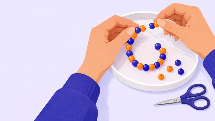 Hands thread orange and indigo beads onto clear cord over a shallow tray